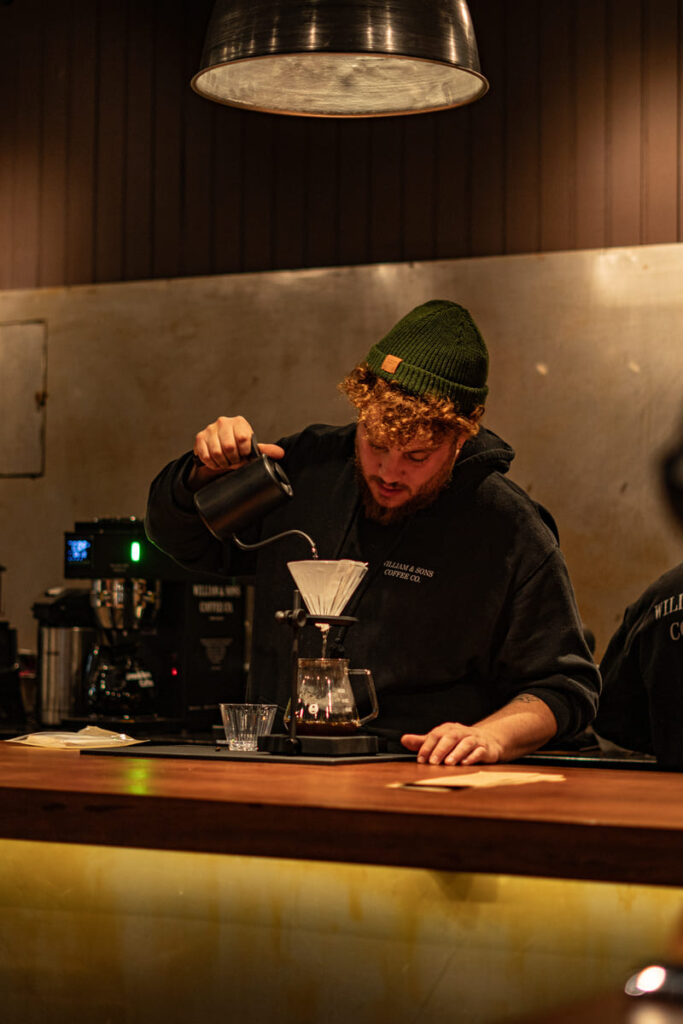 Barista coando café em jarra de vidro