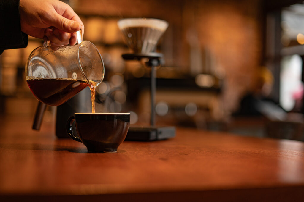 Mão colocando café coado em xícara